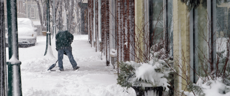Image of a man shoveling snow outside a business